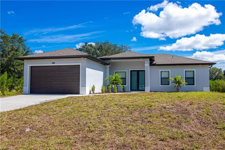 Prairie-style home with a garage, stucco siding, driveway, a front lawn, and roof with shingles