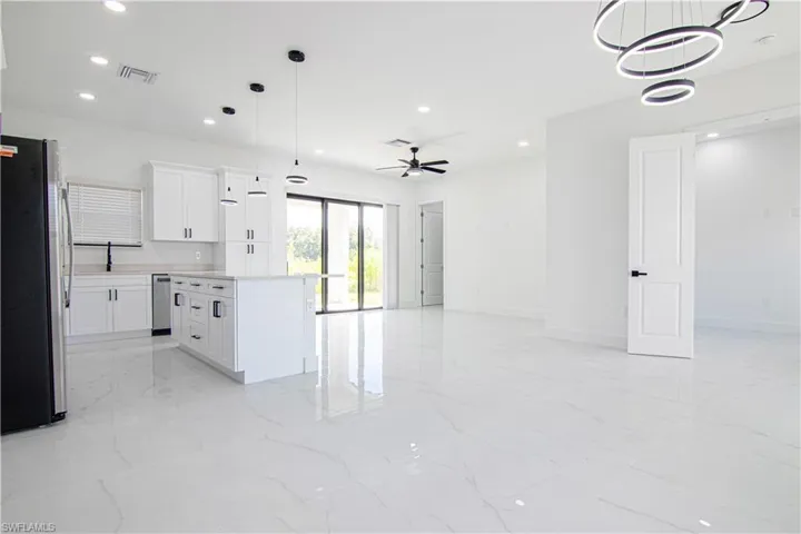 Kitchen featuring freestanding refrigerator, light countertops, a kitchen island, open floor plan, and white cabinetry