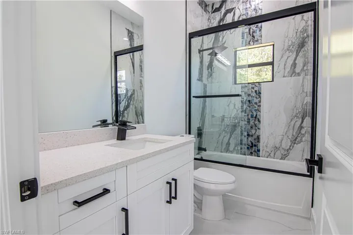 Full bath featuring combined bath / shower with glass door and vanity