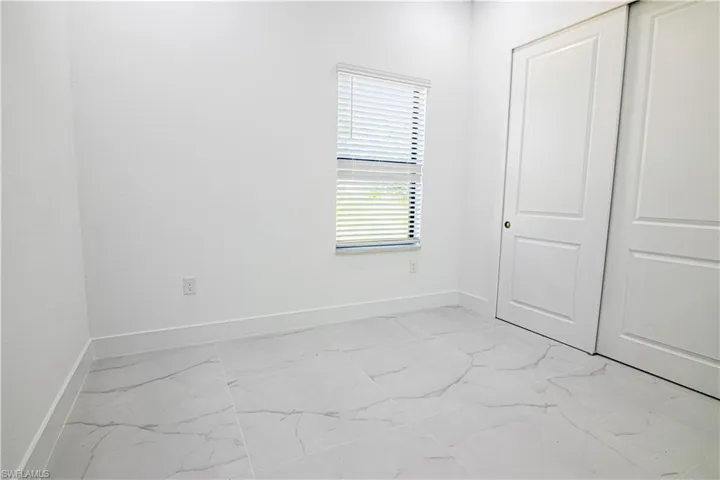 Unfurnished bedroom featuring light marble finish floors and a closet