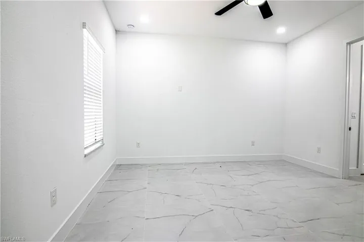 Unfurnished room with ceiling fan, recessed lighting, and light marble finish flooring