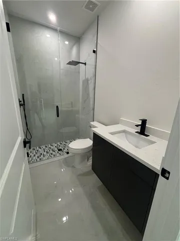 Bathroom with vanity, toilet, and a shower with shower door