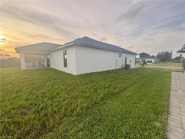 Property exterior at dusk with a yard and central air condition unit