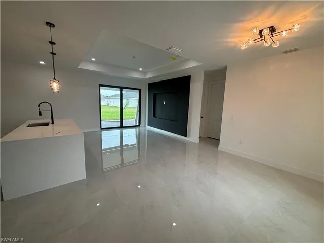 Unfurnished living room with a raised ceiling and sink