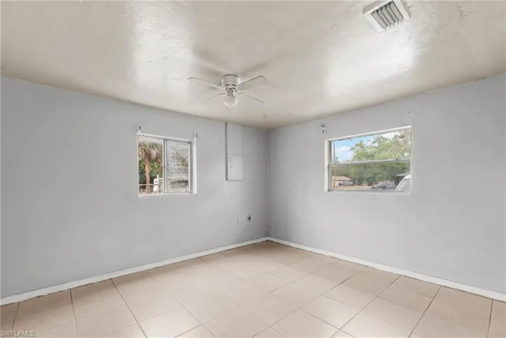 Empty room featuring plenty of natural light, ceiling fan, a textured ceiling, and tile patterned floors