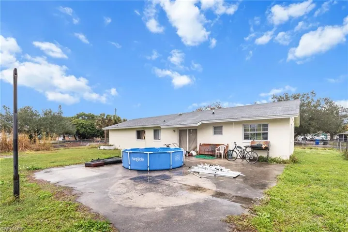 Back of property featuring stucco siding, an outdoor pool, and a patio area