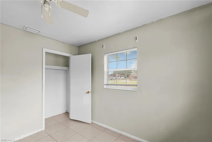 Unfurnished bedroom featuring light tile patterned floors, a closet, and a ceiling fan