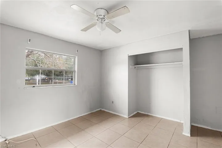 Unfurnished bedroom featuring a closet, light tile patterned floors, and a ceiling fan