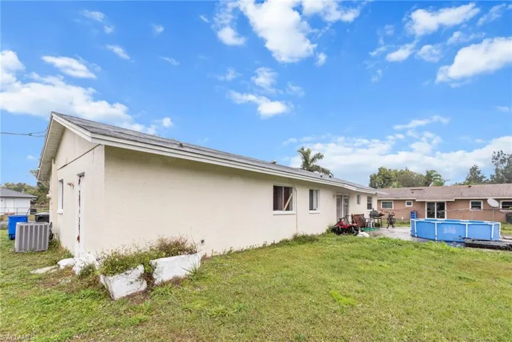 Back of house featuring stucco siding, an outdoor pool, a lawn, and a patio
