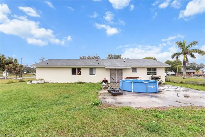Rear view of property featuring stucco siding, an outdoor pool, and a patio area