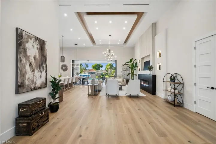 Living area featuring recessed lighting, an inviting chandelier, light wood finished floors, and a raised ceiling
