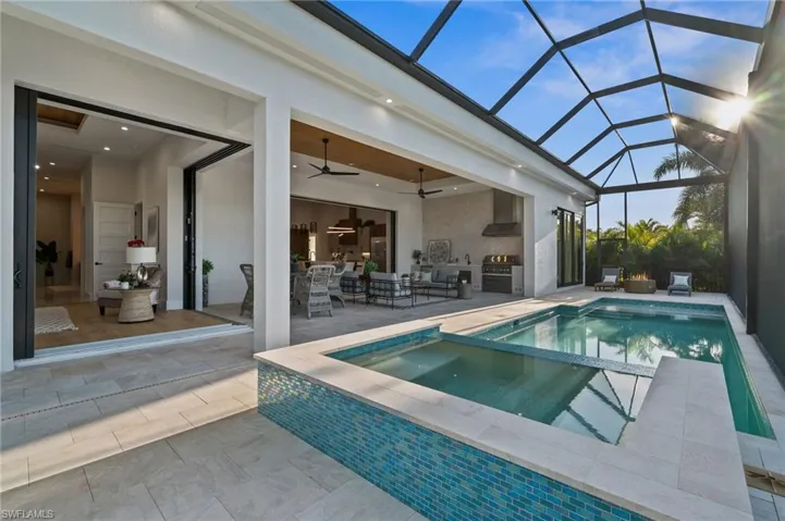View of pool featuring glass enclosure, a patio, ceiling fan, and area for grilling