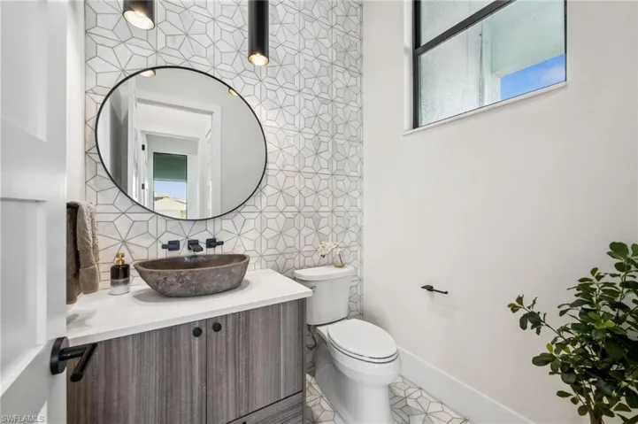 Bathroom with tile patterned floors, toilet, baseboards, backsplash, and vanity
