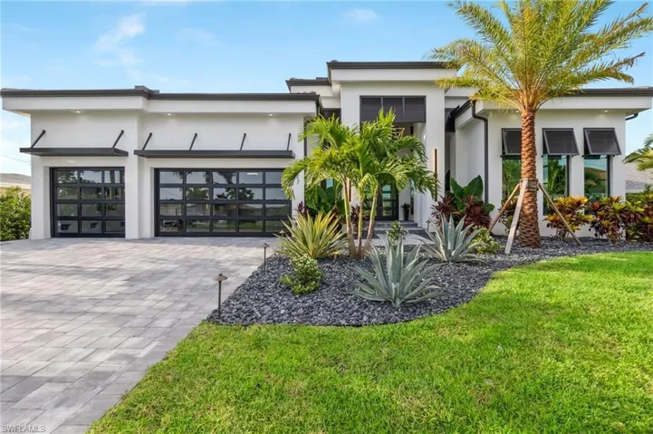 Contemporary home with stucco siding, an attached garage, decorative driveway, and a front lawn