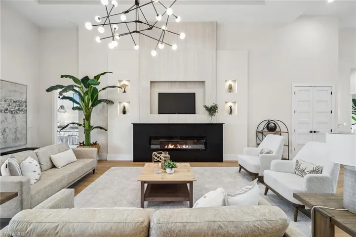 Living room with a glass covered fireplace, wood finished floors, a high ceiling, and baseboards