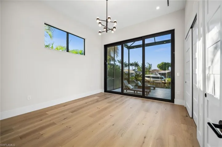 Spare room with plenty of natural light, baseboards, a notable chandelier, and light wood-type flooring