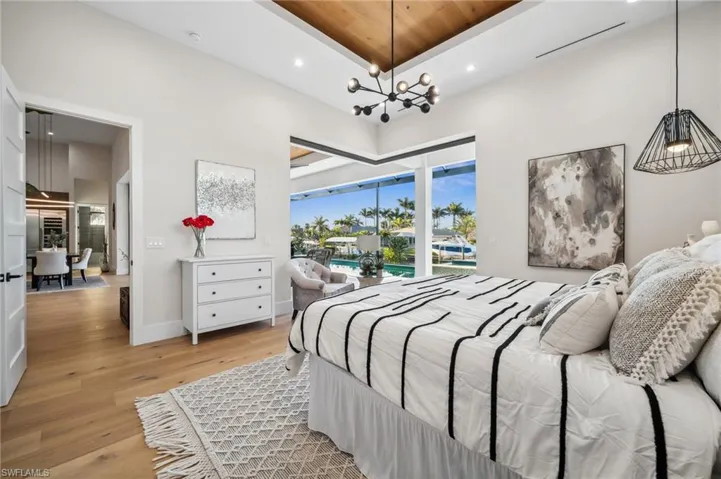 Bedroom featuring recessed lighting, a high ceiling, access to exterior, light wood-type flooring, and a notable chandelier