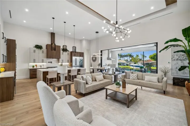 Living room with recessed lighting, light wood-style flooring, a high ceiling, and baseboards