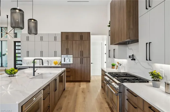 Kitchen with a sink, decorative backsplash, modern cabinets, light wood finished floors, and high end stainless steel range oven