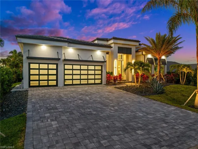 View of front of property with stucco siding, decorative driveway, and a garage