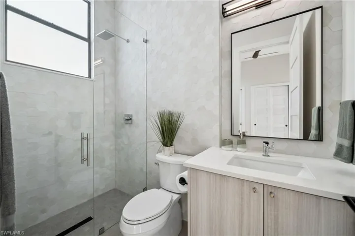 Full bath with toilet, vanity, and a stall shower
