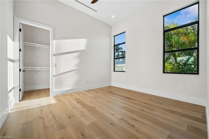Unfurnished bedroom featuring ceiling fan, lofted ceiling, wood finished floors, and baseboards