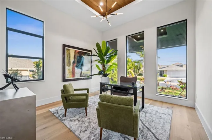 Sitting room featuring plenty of natural light, baseboards, an inviting chandelier, and light wood-style floors