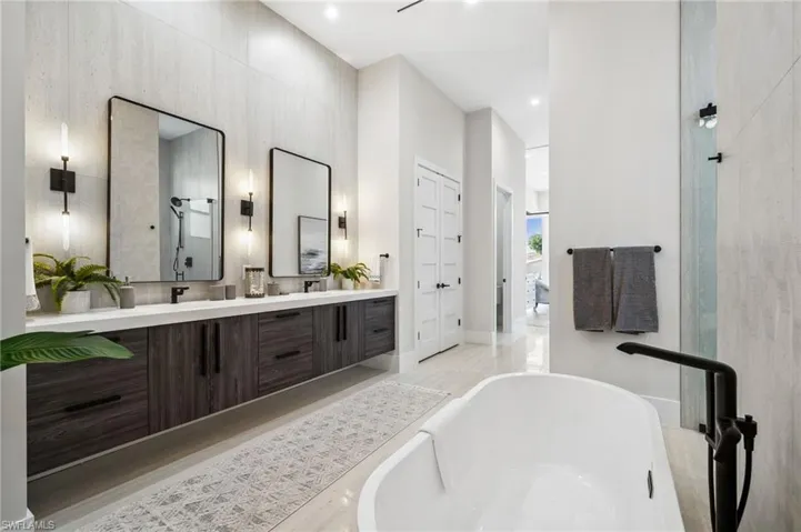 Full bathroom with a freestanding bath, double vanity, baseboards, and wood finished floors