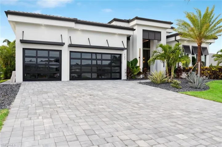 Contemporary house with stucco siding, an attached garage, and decorative driveway