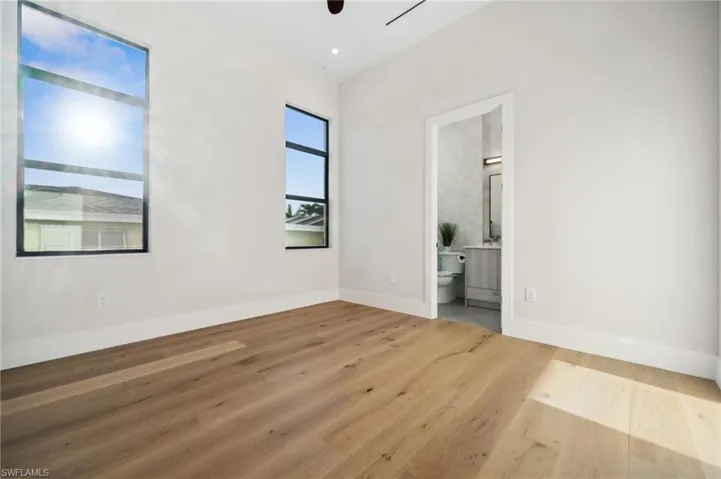 Unfurnished bedroom with baseboards, wood finished floors, and ensuite bathroom
