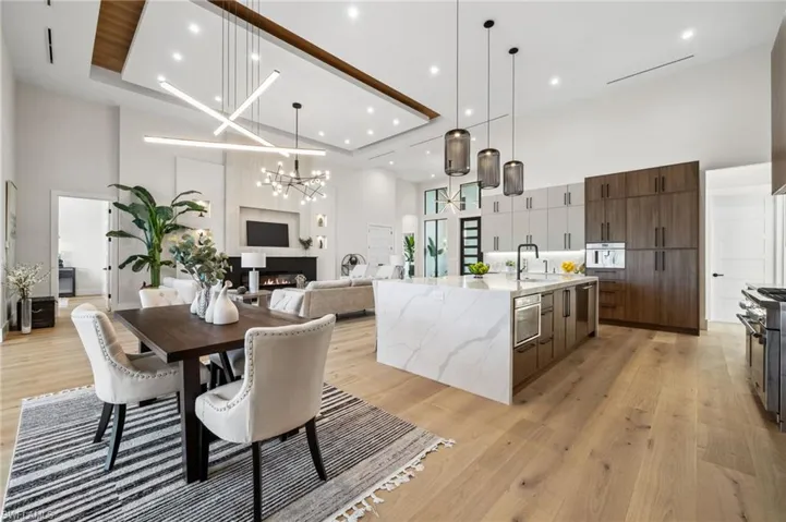 Dining space with a large fireplace, a notable chandelier, a towering ceiling, and light wood finished floors