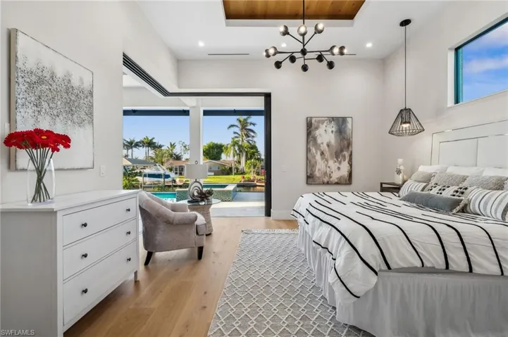 Bedroom featuring multiple windows, an inviting chandelier, light wood finished floors, and access to exterior