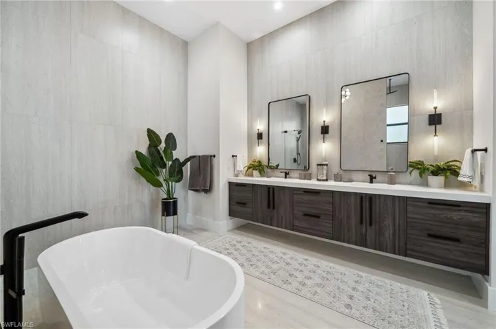 Full bathroom featuring a soaking tub, a sink, double vanity, a high ceiling, and wood finished floors