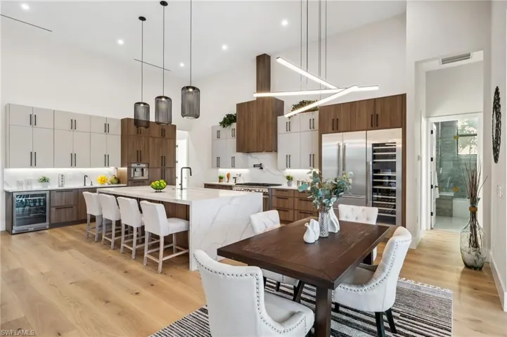 Dining space with visible vents, recessed lighting, light wood-style floors, high vaulted ceiling, and beverage cooler