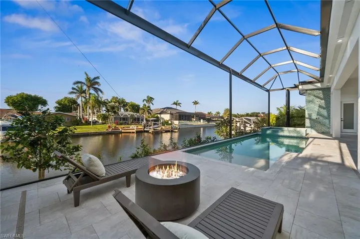 Outdoor pool with a fire pit, a water view, a patio, and a lanai