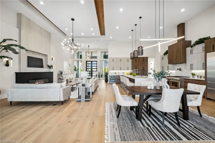 Dining area featuring a chandelier, light wood-style floors, a fireplace, a high ceiling, and recessed lighting