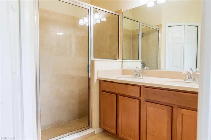 Full bathroom with a shower stall, double vanity, and tile patterned flooring