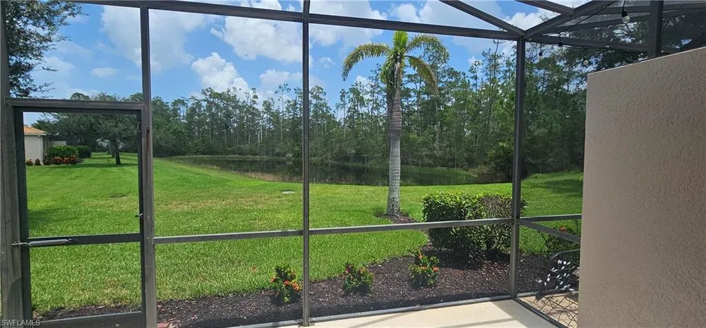 Unfurnished sunroom featuring a water view and view of wooded area