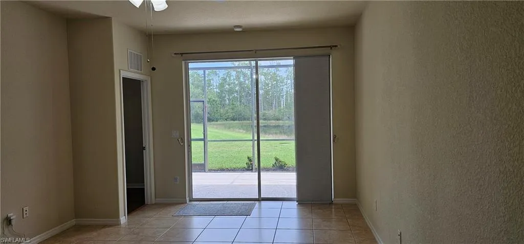 Doorway with light tile patterned floors, a textured wall, and a ceiling fan