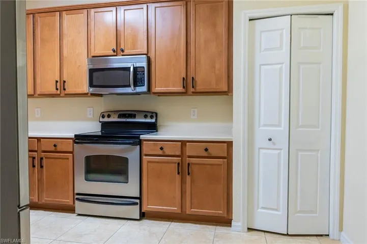 Kitchen featuring appliances with stainless steel finishes, light countertops, brown cabinetry, and light tile patterned floors