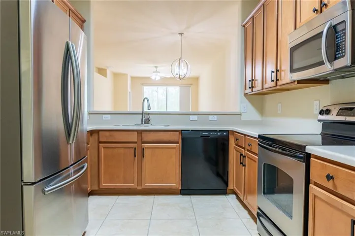 Kitchen with appliances with stainless steel finishes, a sink, brown cabinets, and light countertops