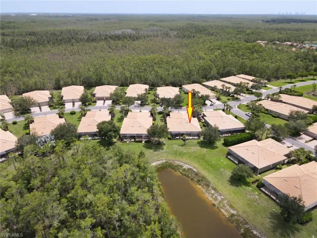 Aerial view of residential area featuring a heavily wooded area and a nearby body of water