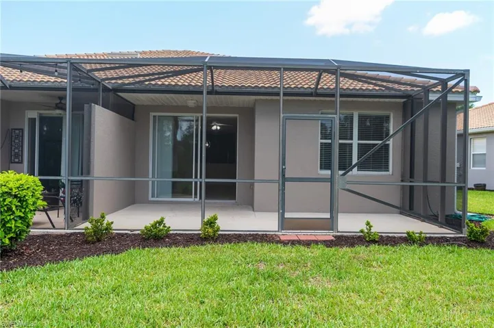 Rear view of house featuring stucco siding, a yard, a tile roof, and a patio area