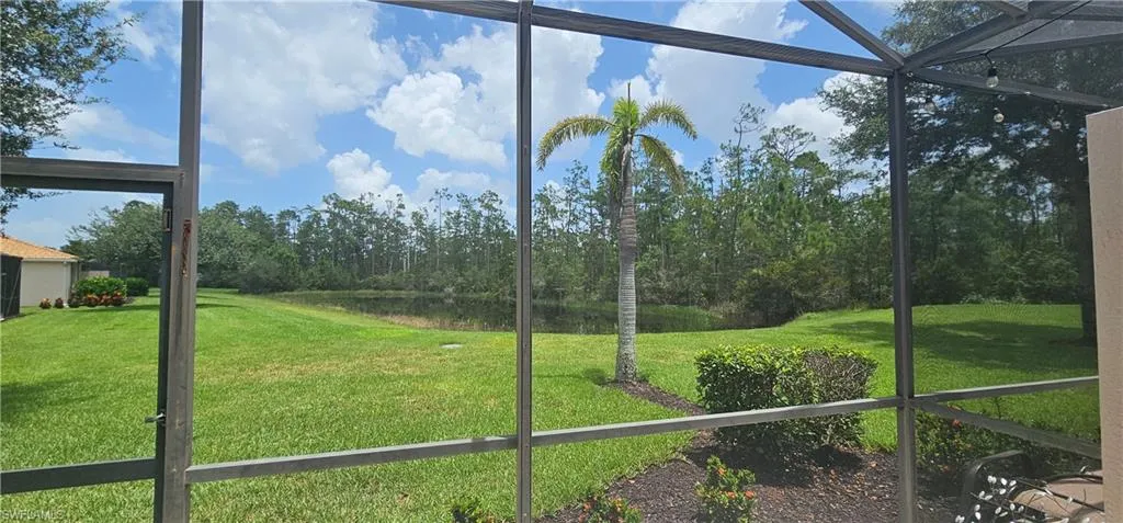 Unfurnished sunroom featuring a water view and view of wooded area