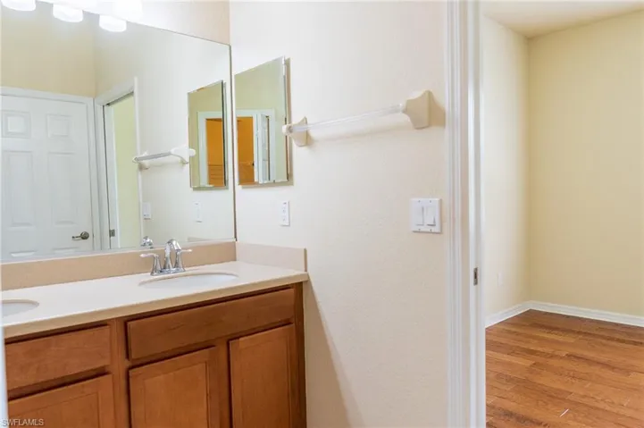 Bathroom featuring double vanity, wood finished floors, and baseboards