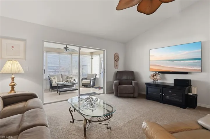 Living room with a ceiling fan, carpet, and vaulted ceiling