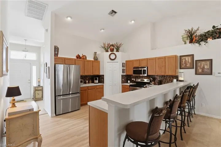 Kitchen featuring stainless steel appliances, a peninsula, a kitchen breakfast bar, light countertops, and tasteful backsplash