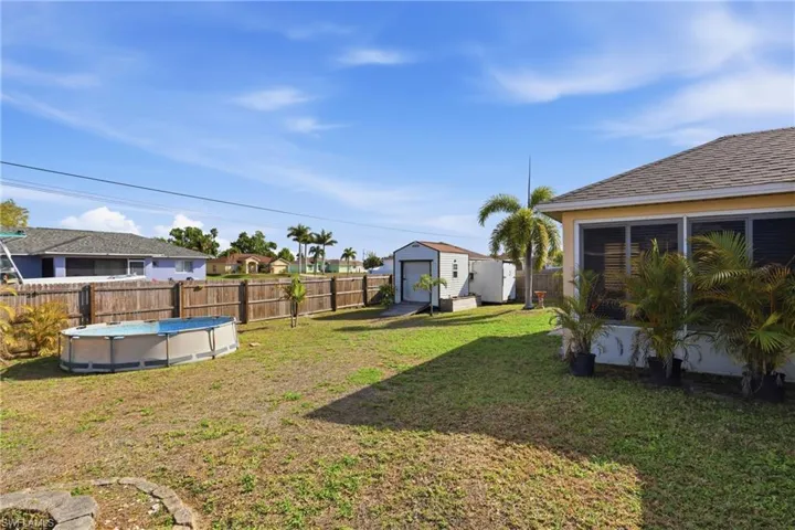 Fenced backyard featuring a residential view and a storage unit