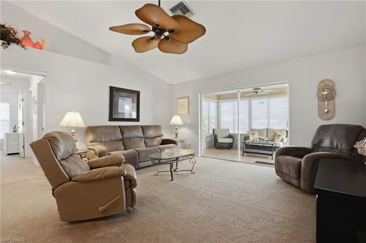 Living area with carpet floors, ceiling fan, and lofted ceiling