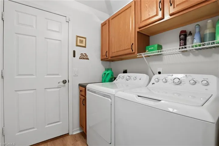 Laundry room featuring washer and dryer, cabinet space, and light wood-style flooring